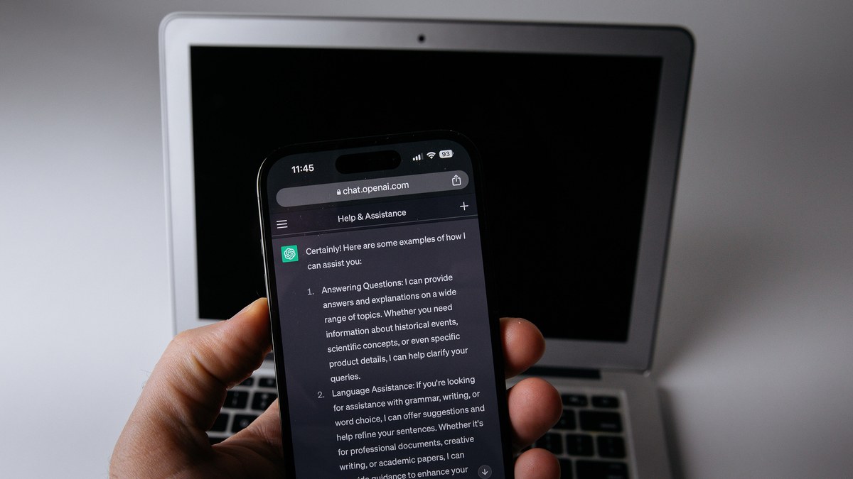Elde tutulan akıllı telefonda açık ChatGPT sohbeti, arkada dizüstü bilgisayar (temsili görsel)