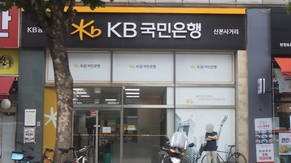 Güney Kore'de KB Kookmin Bank şubesinin girişi; siyah zemin üzerinde sarı KB logolu banka tabelası