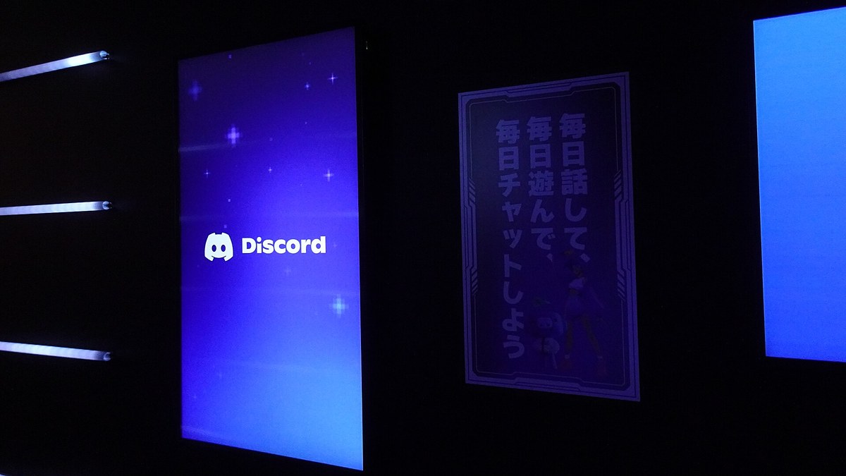 Tokyo Game Show 2024'teki Discord standında, karanlık duvarda Discord logosu gösteren dikey ekran