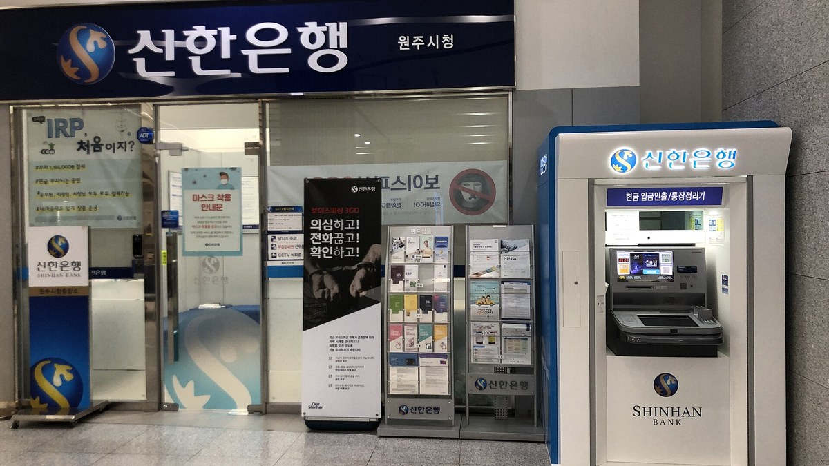 Güney Kore'de bir Shinhan Bank şubesinin girişi ve yanında Shinhan Bank ATM'si; tabelada Korece banka adı