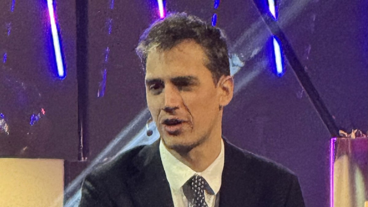 Mistral AI CEO'su Arthur Mensch, mor ve mavi sahne ışıkları önünde bir panelde konuşurken