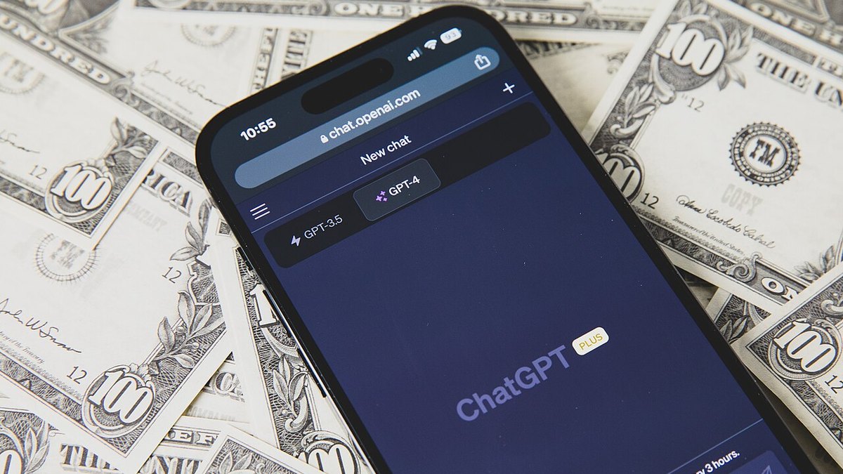 Dolar banknotlarının üzerinde, ekranında ChatGPT açık bir akıllı telefon