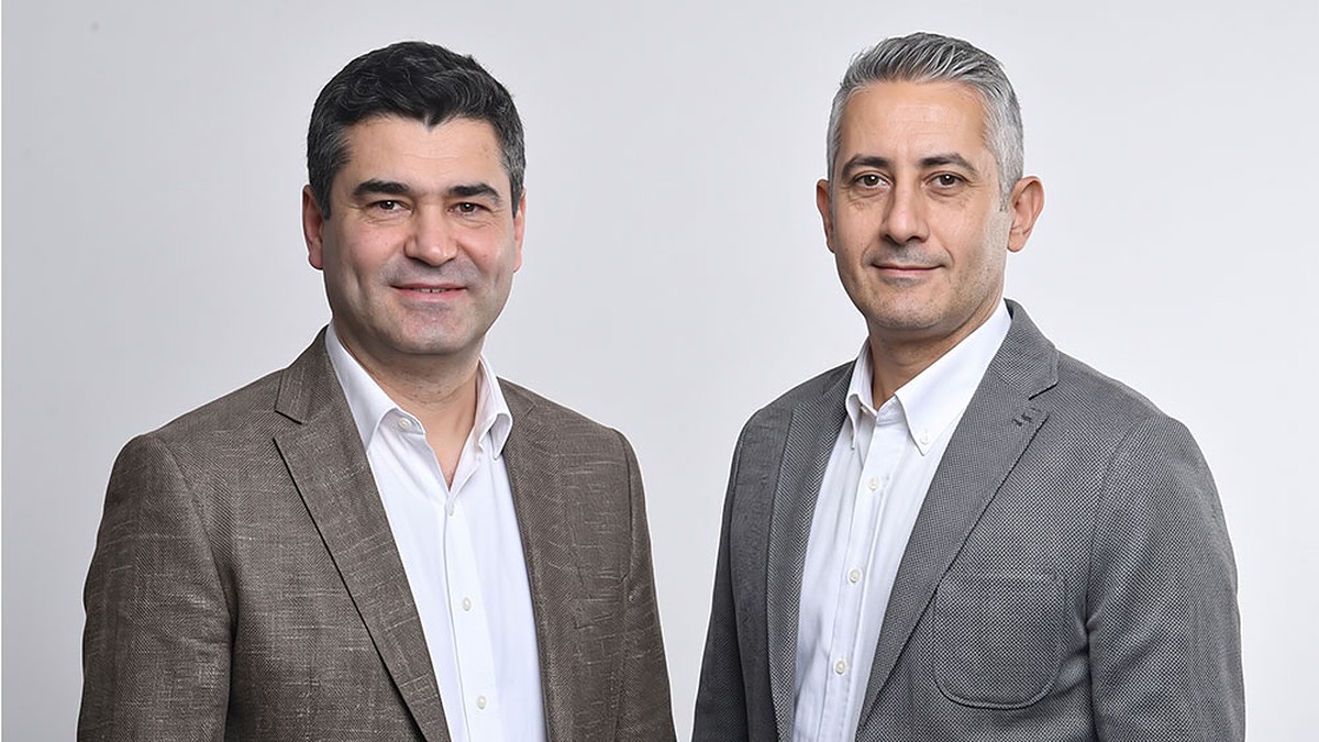 Softtech Genel Müdürü M. Bülent Özçengel ve İşNet Genel Müdürü Mehmet Fahri Can, açık gri zemin önünde yan yana