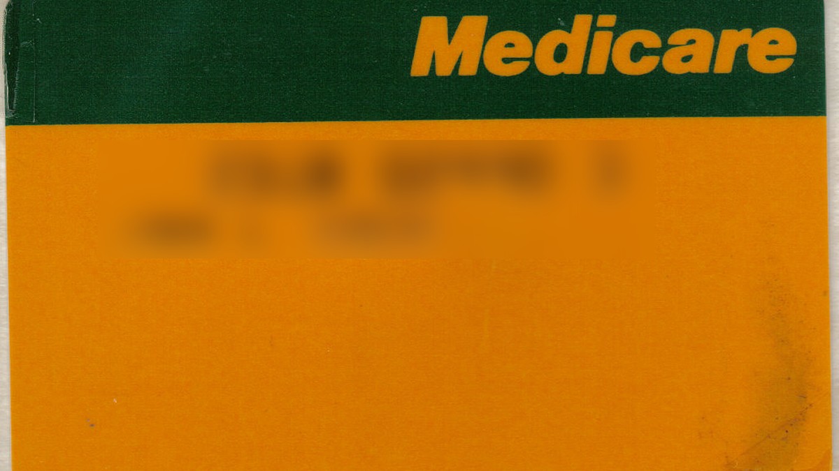 Yeşil şerit üzerinde sarı Medicare yazısı bulunan turuncu Avustralya Medicare kartı; kart numarası ve ad bulanık